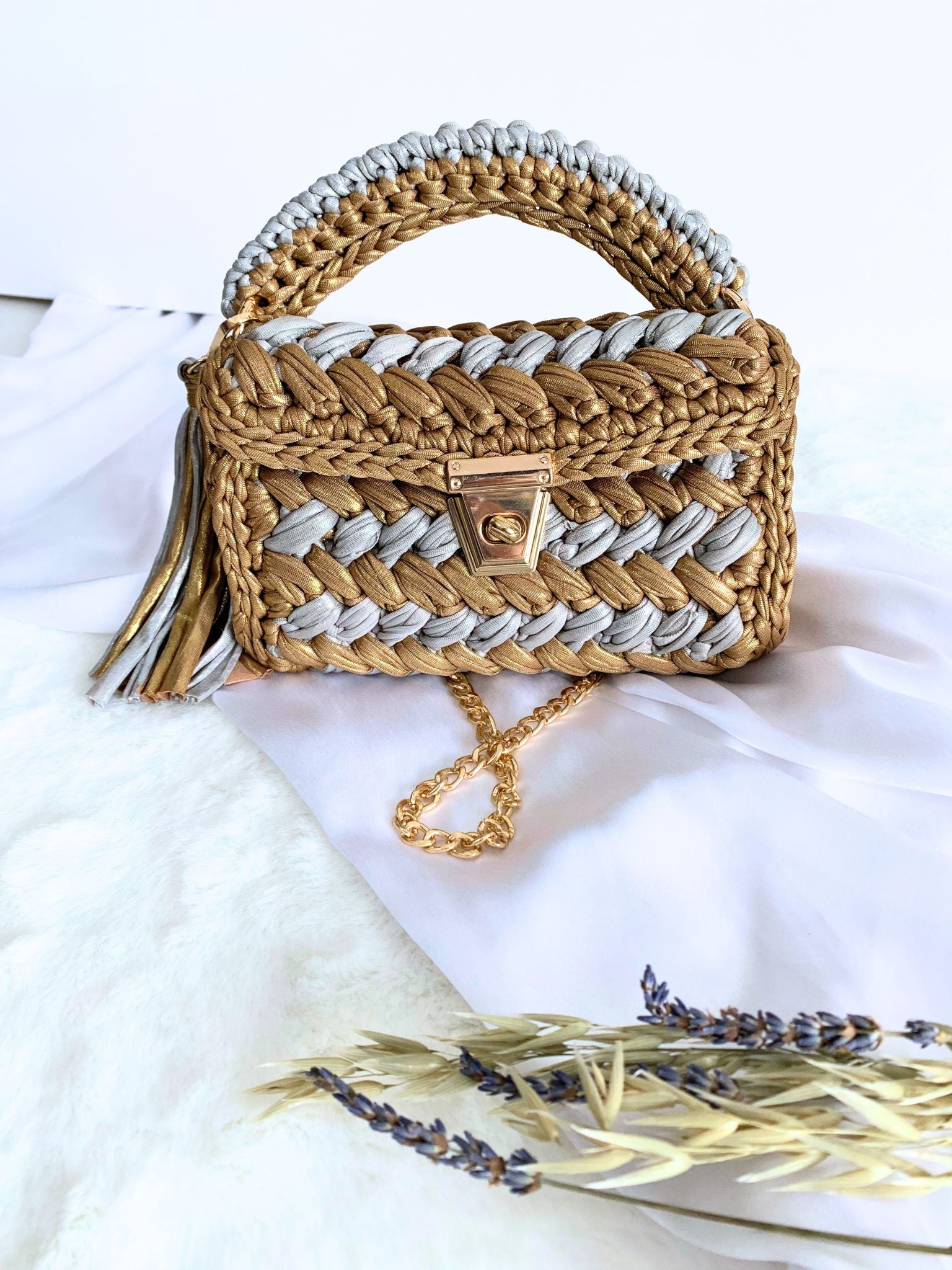 Detachable chain adds practicality to the meticulously crafted gold and silver crochet handbag.