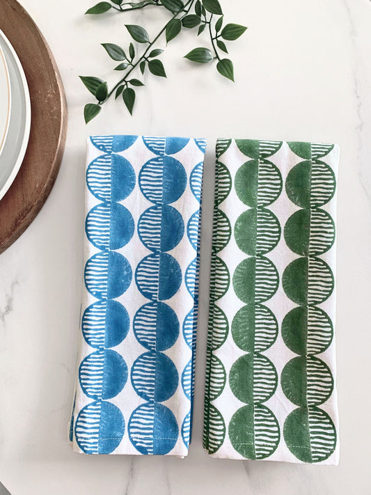 A pair of eco-friendly tea towels, block-printed with rhythmic circles on organic cotton, offering a sustainable alternative to paper towels.