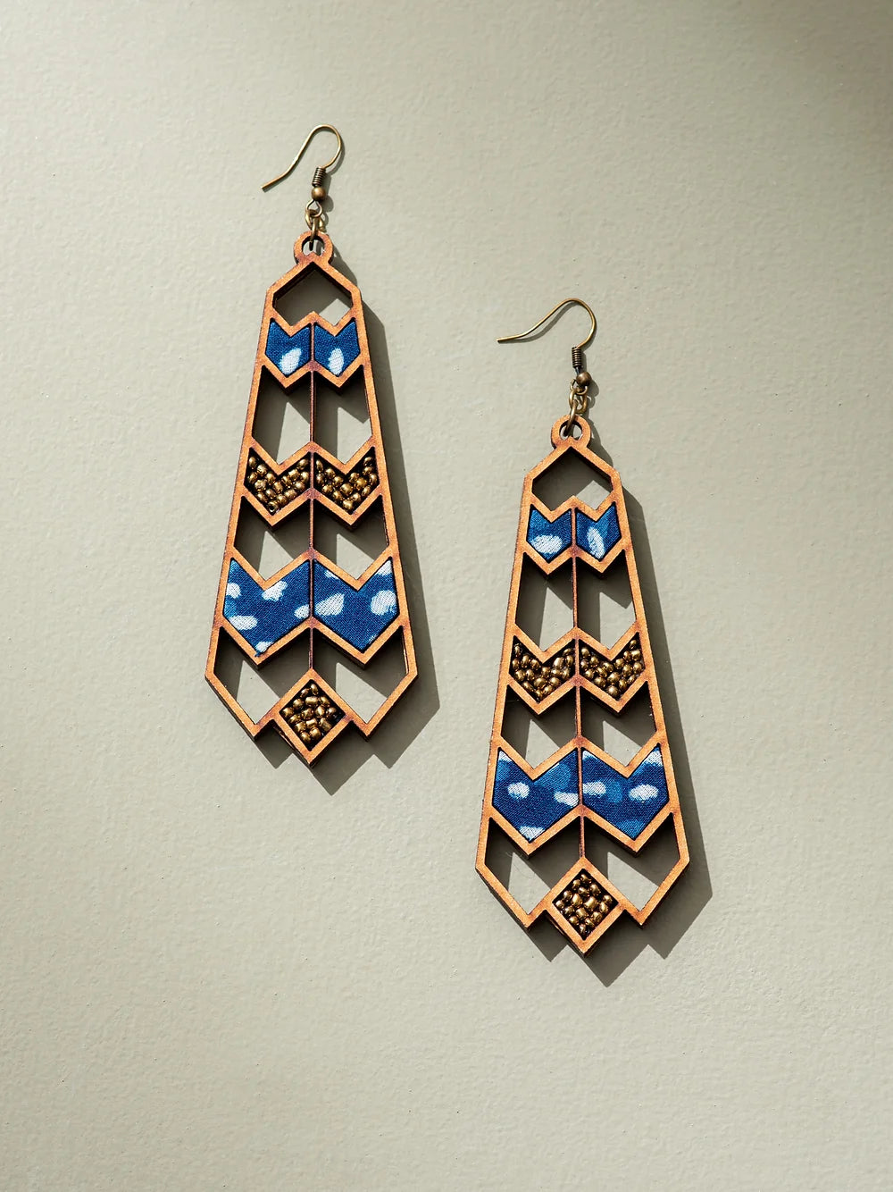 Intricate wave pattern danglers crafted from upcycled wood and fabric.