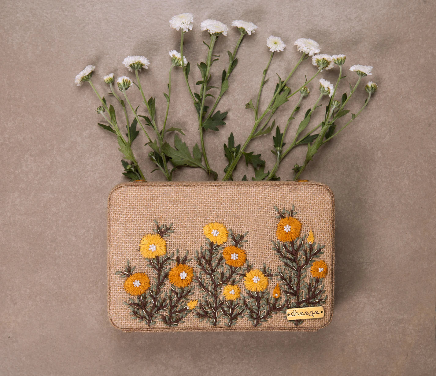 Adorned with yellow & orange embroidered buttercups, this box clutch adds a touch of sophistication to your outfits.