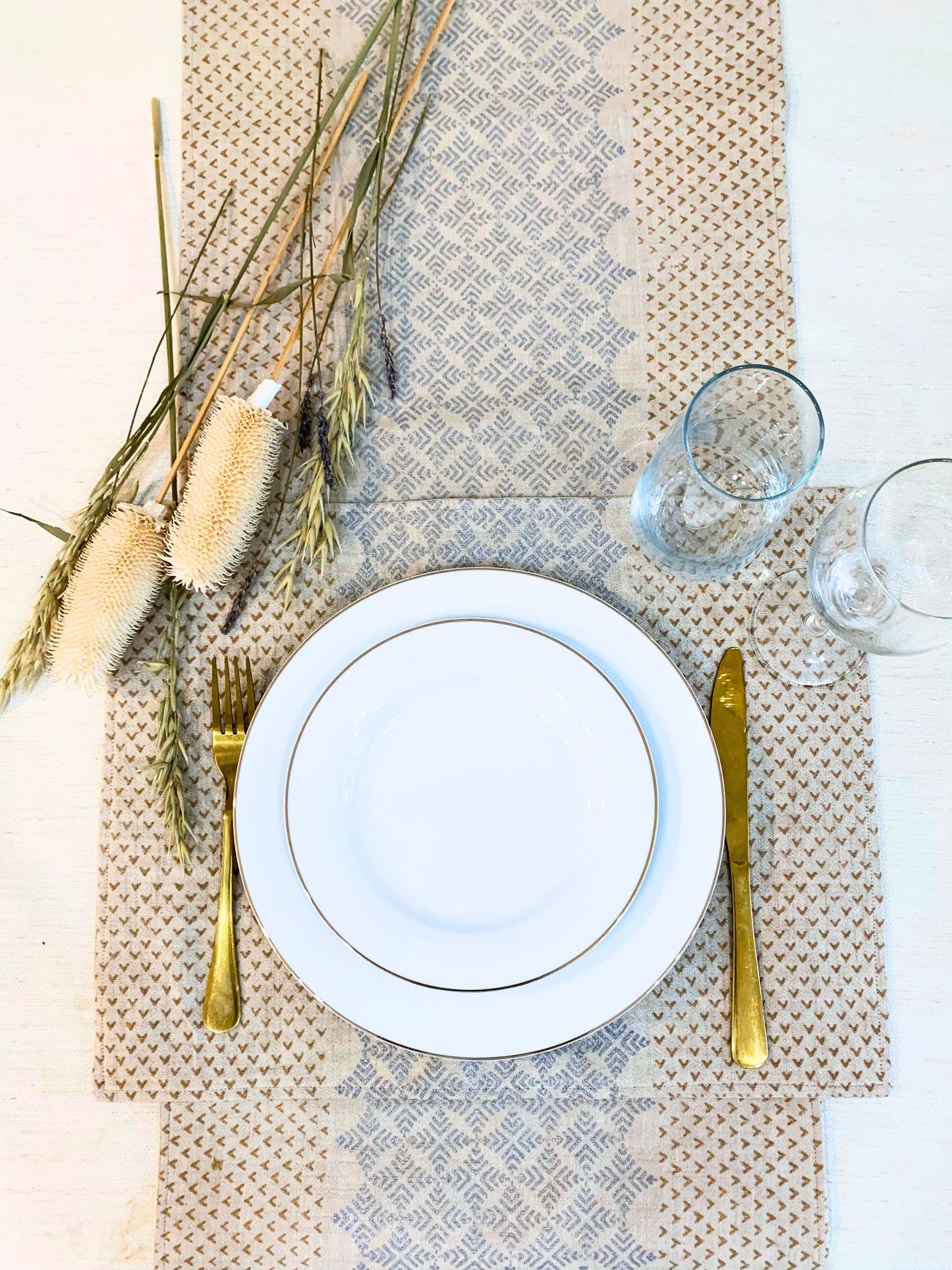 GOTS certified organic cotton table runner in natural-beige, showcasing an elegant geometric pattern with block-printed dull gold and silver accents for a touch of glamour at house parties.