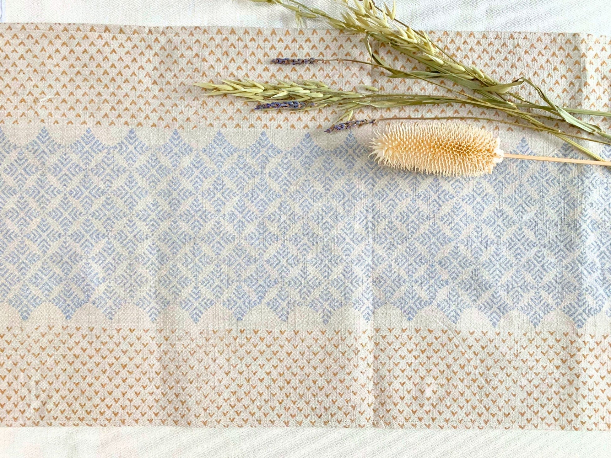 GOTS certified organic cotton table runner with an elegant geometric pattern, block-printed with dull gold and silver accents on a natural-beige fabric for a touch of glamour.