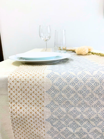 Elevate your table setting with this GOTS certified organic cotton table runner, adorned with an elegant geometric pattern and block-printed dull gold and silver accents on a natural-beige fabric.