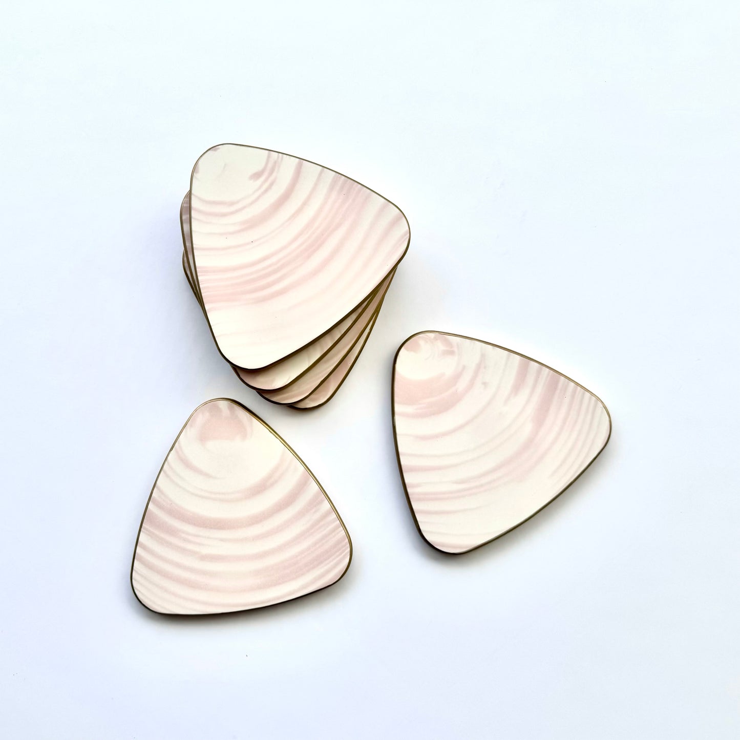 Triangular coasters in white and pink with a gold border