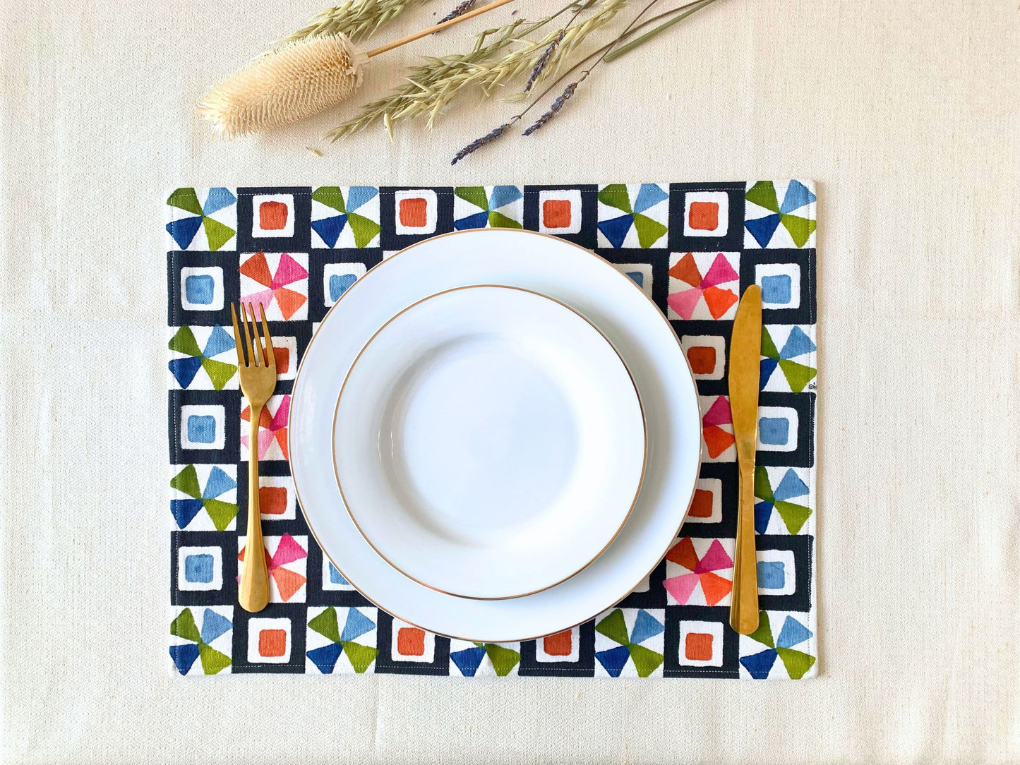 block printed placemats featuring an unconventional geometric pattern in a spectrum of colors, designed to complement plain crockery. Crafted from GOTS certified organic cotton with a double-layered construction for durability, style, and sustainability.