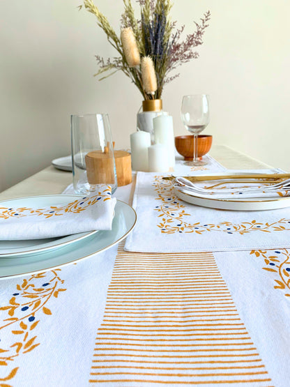 Elevate your dining experience with a table runner made from GOTS certified organic cotton, featuring a block-printed floral pattern and clean lines in mustard color for a touch of sophistication.