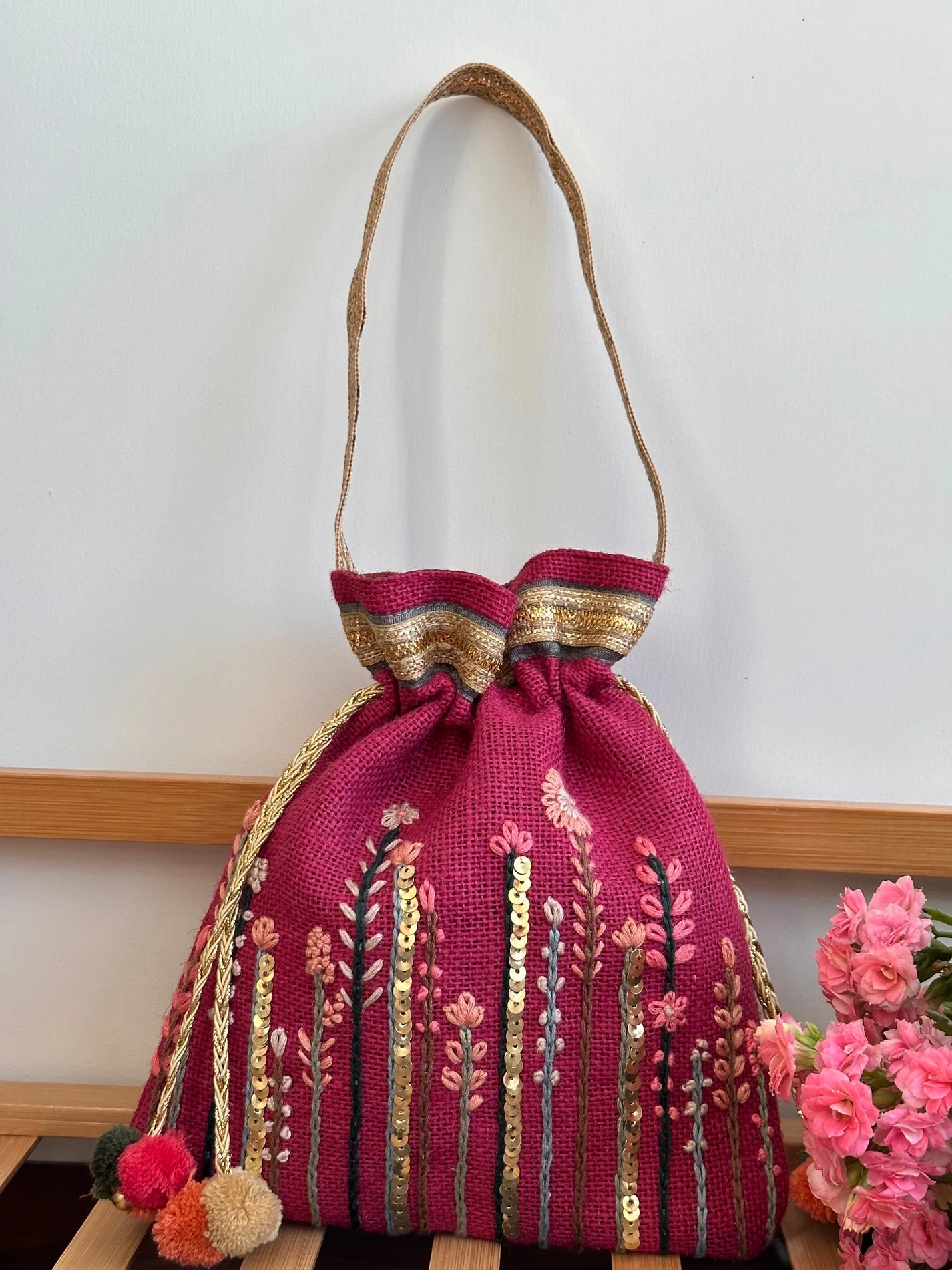 Bright pink potli bag with embroidered flowers.