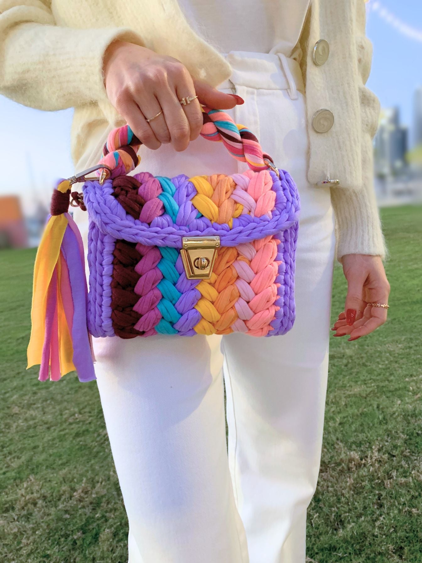 Handcrafted crochet bag in a spectrum of colors on a purple base.