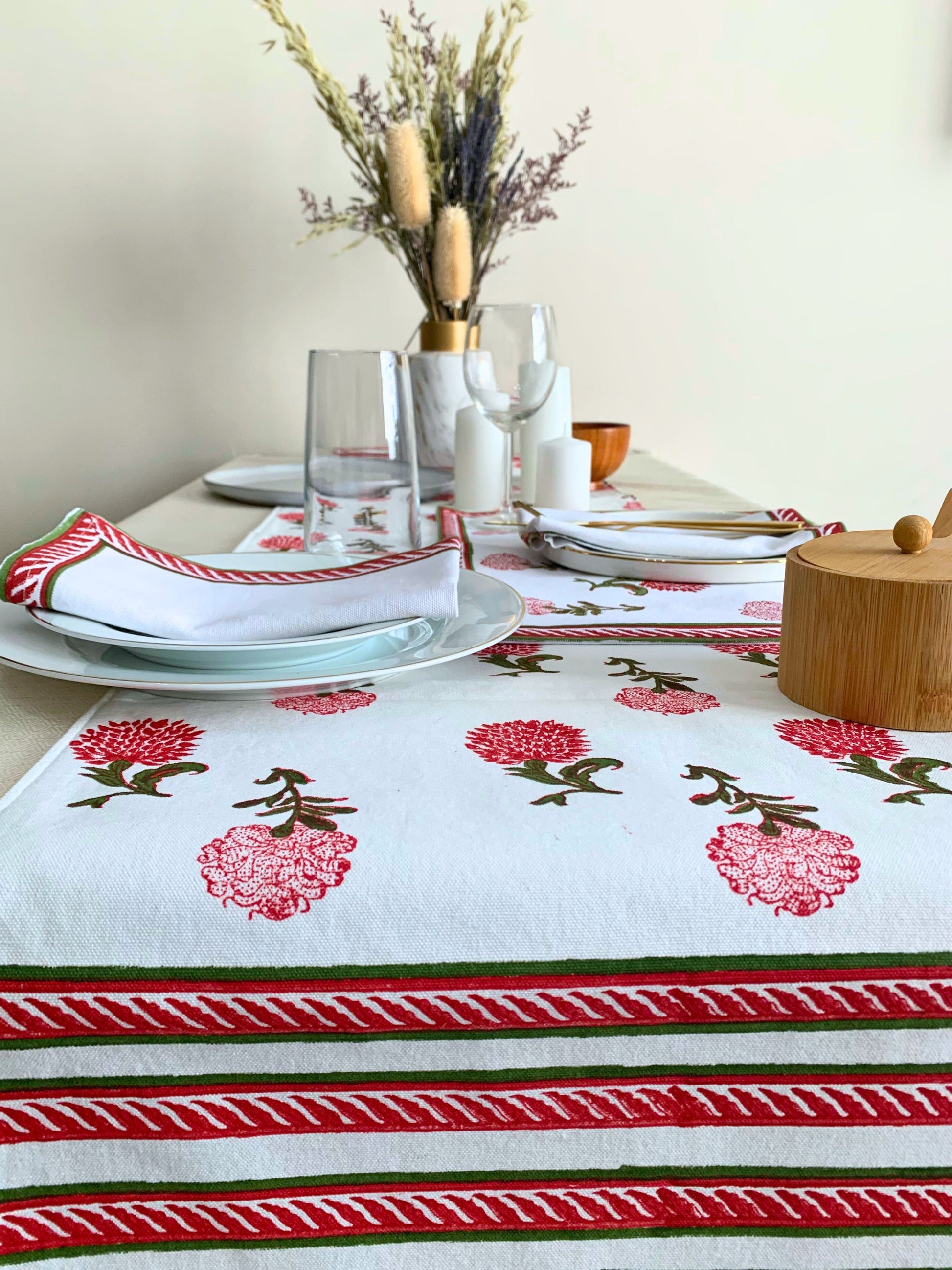 Elevate your dining experience with this white table runner featuring delicate block printed motifs in vibrant red and green on GOTS certified organic cotton.