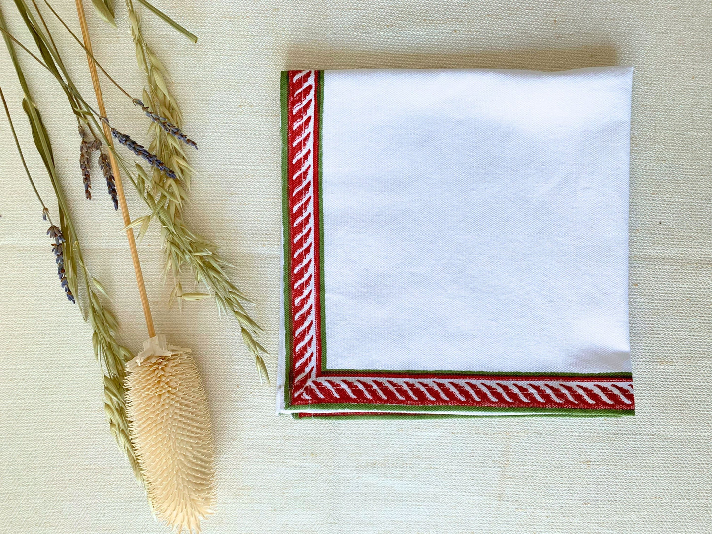 Set of 6 napkins with a vibrant red and green block printed border, adding a pop of color to your table setting. Crafted from GOTS certified organic cotton for an environmentally conscious lifestyle.