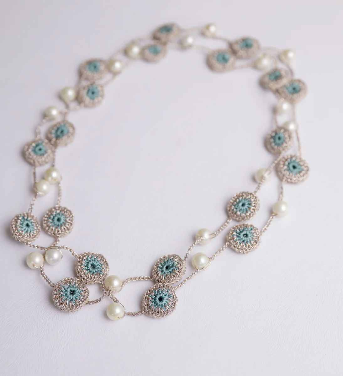 Stylish and lightweight necklace adorned with crochet motifs and pearls in blue..