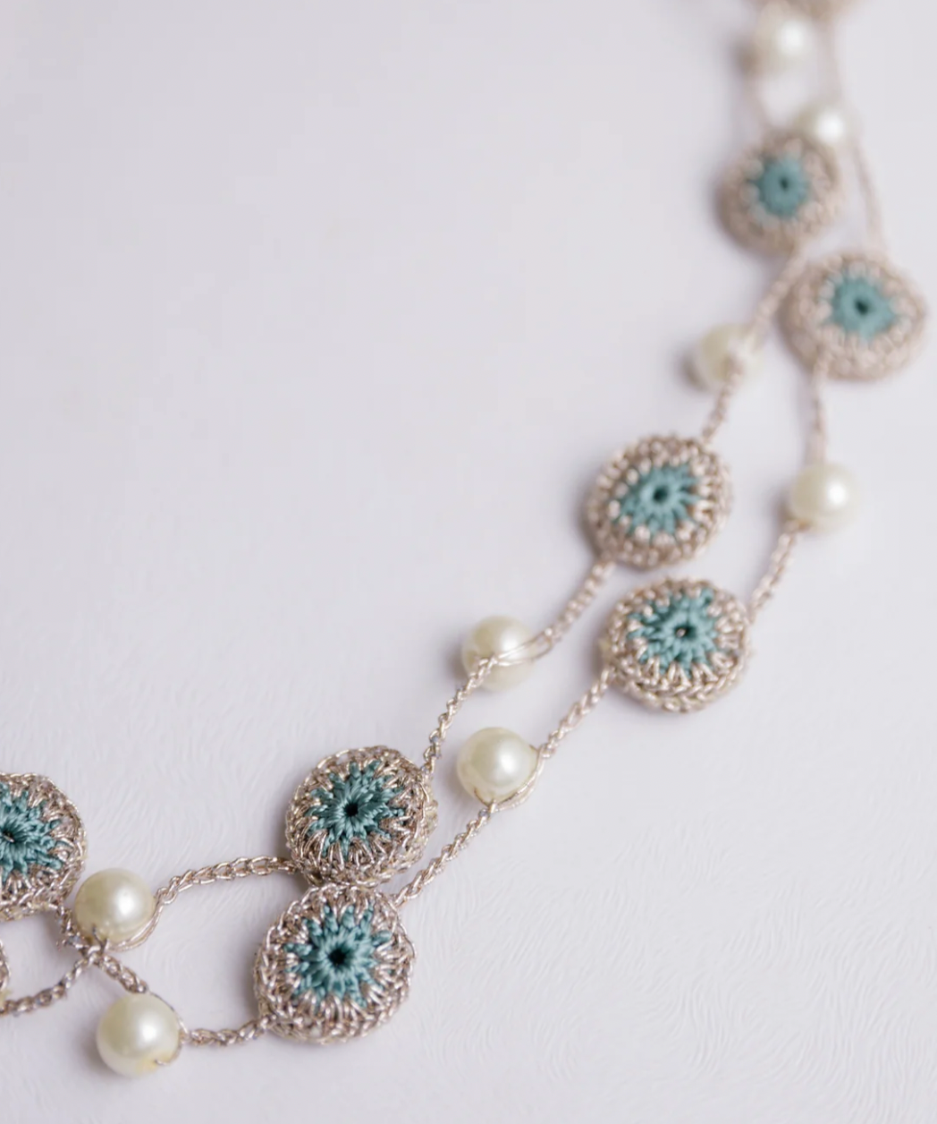 Stylish and lightweight necklace adorned with crochet motifs and pearls.