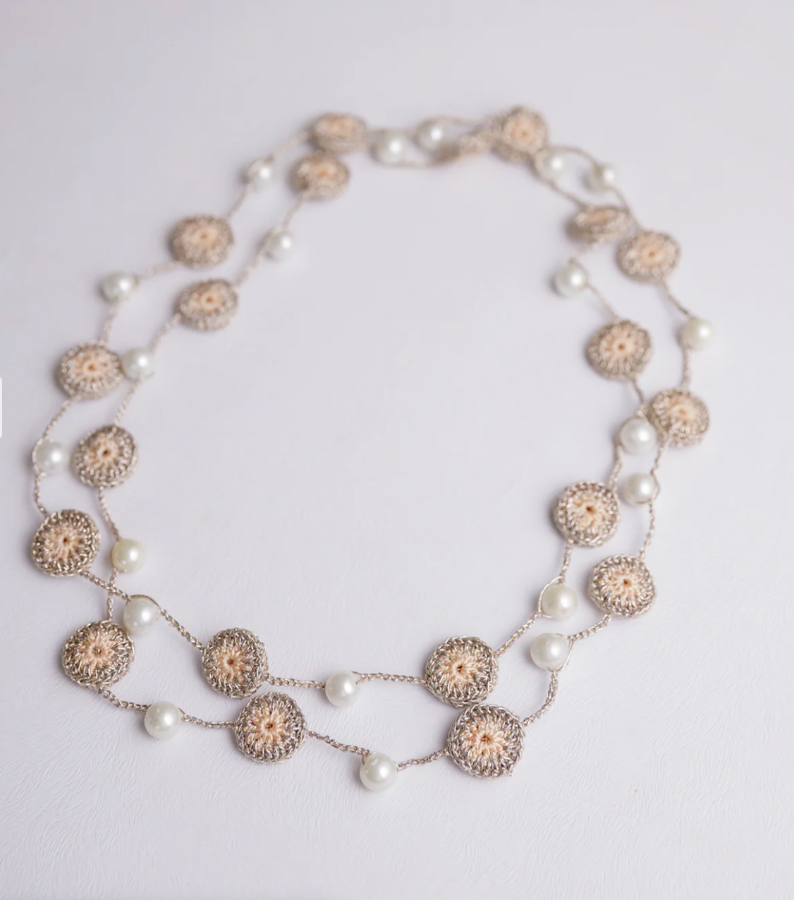 Elegant crocheted necklace in beige with delicate motifs and lustrous pearl beads.