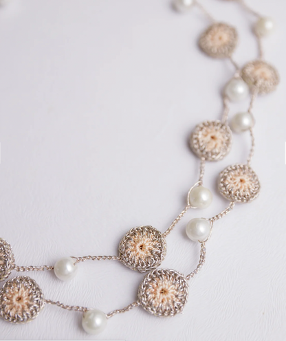 Charming beige handcrafted necklace combining lightweight design, crochet, and pearls.