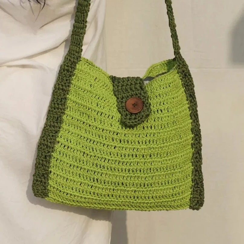 Green hobo bag, meticulously crocheted using top-tier acrylic yarn. The wooden button closure enhances its sophisticated design in a burst of bright colors.