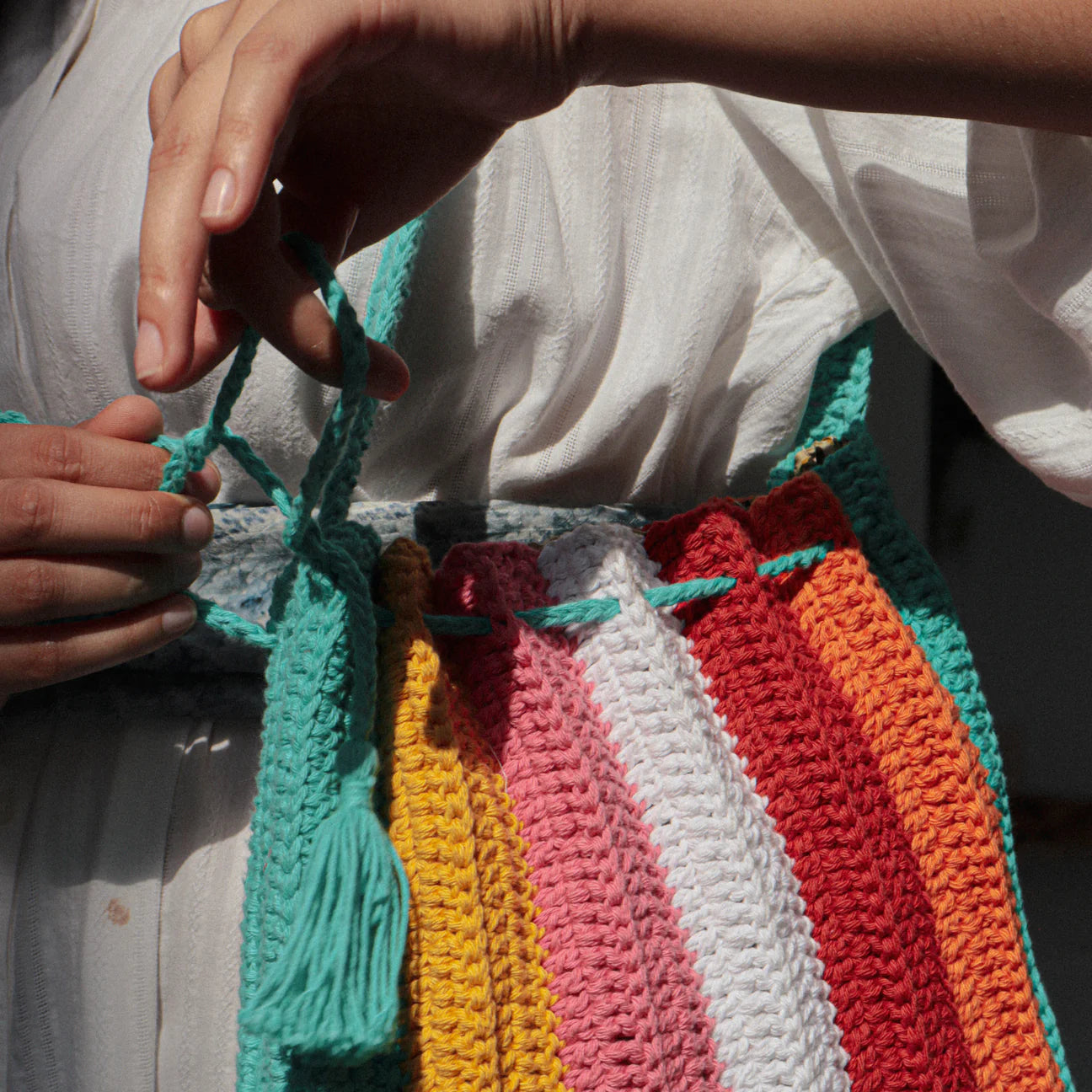 hand-crocheted 100% cotton tote bag, boasting a drawstring closure and a lively spectrum of colors.