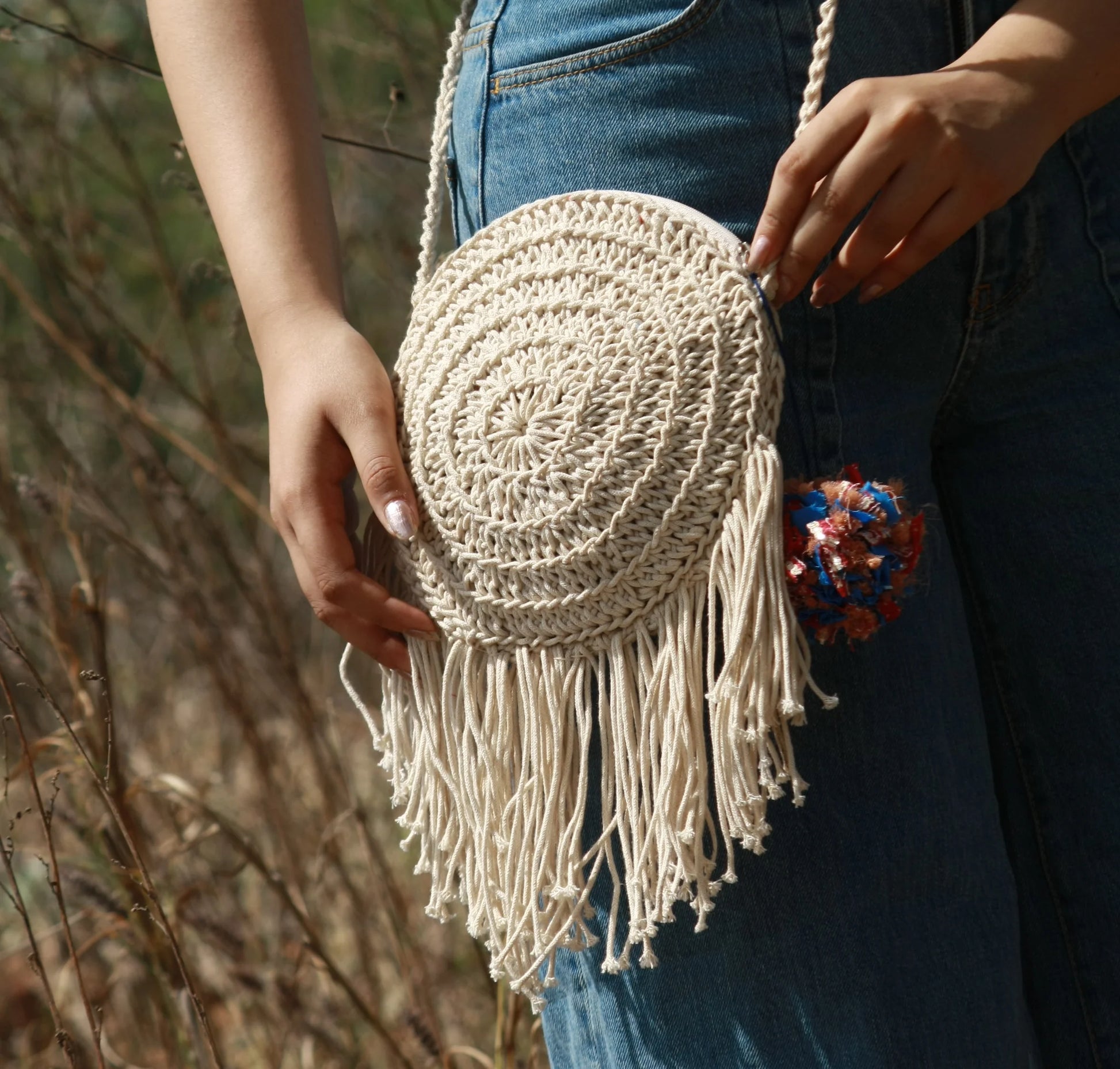 hand-crocheted round cotton bag, showcasing playful tassels and a secure zipper closure