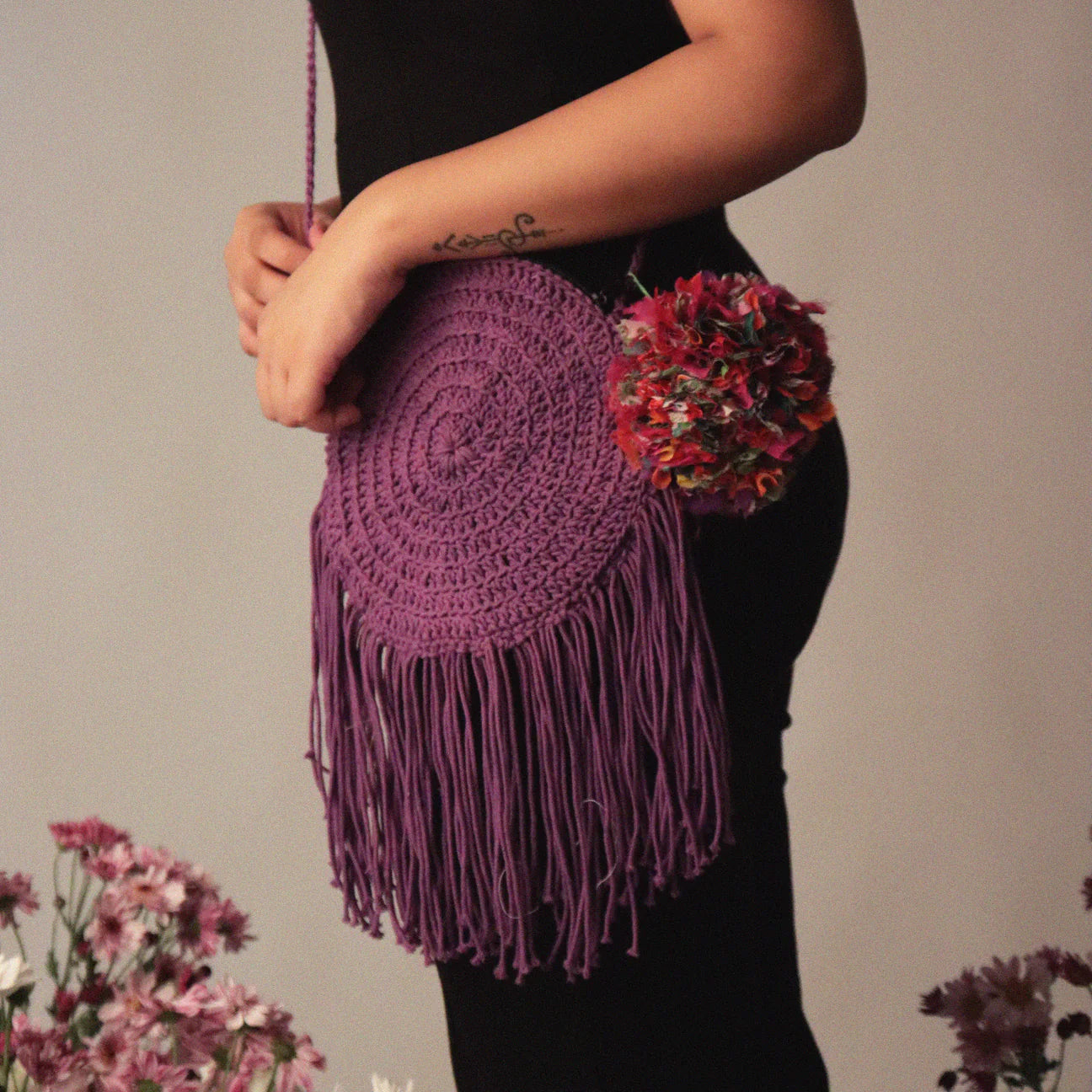 Wine colored hand-crocheted round cotton bag, featuring playful tassels and a secure zipper closure, crafted with 100% cotton yarn.